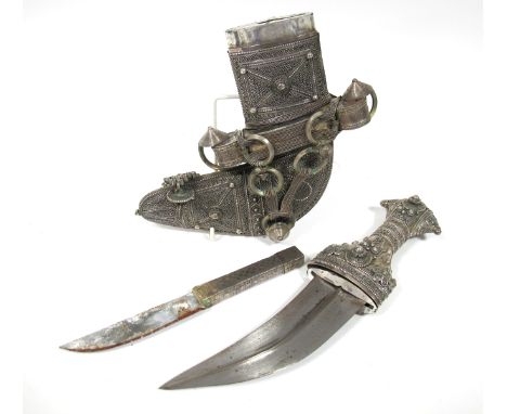 An Omani Khanjar, with shaped twin edge blade, with elaborately decorated white metal grip, conforming scabbard, XX Century.