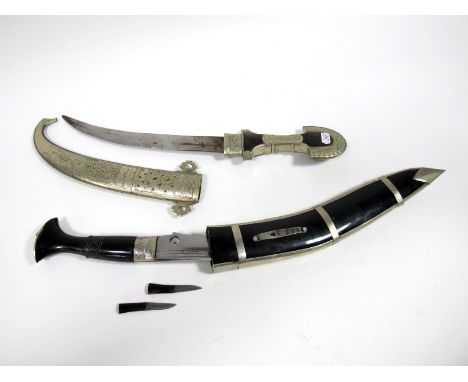 A Berber Dagger, with curved twin edge blade, white metal-mounted wood grip, conforming scabbard, XX Century; A Kukri-Style K