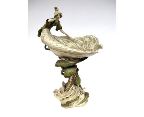 An Art Nouveau Royal Dux Porcelain Centrepiece, modelled as a lady leaning against a shell shaped bowl,m raised on sinuous fo