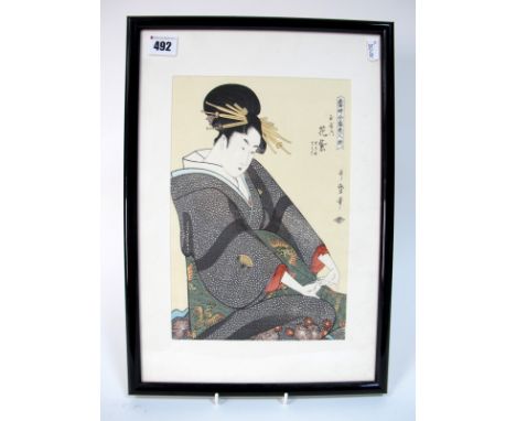 An Early XX Century Japanese Woodcut Print, the seated lady wearing an elaborate black and green kimono decorated with phoeni