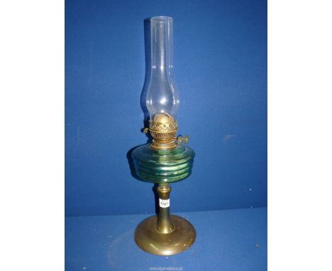 A double burner oil lamp with brass base, turquoise glass reservoir and clear chimney.