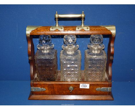 An Oak Tantalus with three hobnail cut decanters, complete with key (some chips to decanters), 14'' wide x 14'' high.