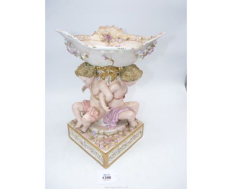 A late 19th century Sitzendorf porcelain flower encrusted table centrepiece with three putti/cherub figures linked supporting