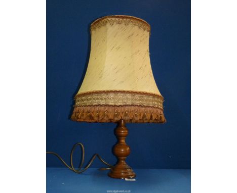 A turned wood Lamp base with fringed and tasselled beige shade, 24'' tall.