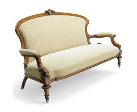 Victorian walnut framed settee, the arched cresting rail with central cartouche decorated with curled acanthus leaves, uphols