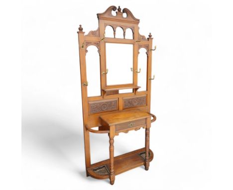 Late Victorian walnut hallstand, scrolled pediment with central finial over rectangular bevelled mirror plate, decorated with