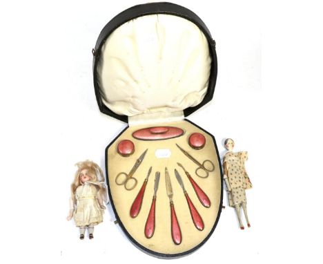 A cased coral pink enamel manicure set, a bisque head doll and another doll 