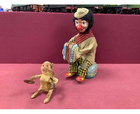 A Mid XX Century Battery Operated Tin Plate Toy Model Automaton of a Clown playing an accordion, attached monkey with glass e