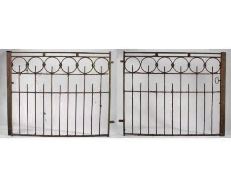 A pair of iron garden gates, each gate with six roundels to the top above railed lower sections, each gate 138cm wide, 112cm 