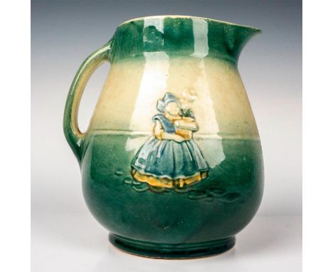 Glazed finish handled pitcher embossed with Dutch scenes on each side that are set against a green and cream colored ground. 