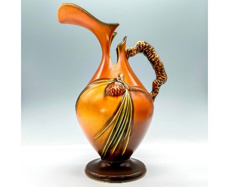 This pitcher features an urn shape, characterized by a rounded body with a narrow neck and a flared spout. The warm brown ton