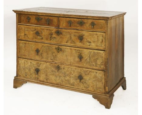 A Queen Anne walnut chest of drawers, with quarter veneered top, above two short and three long drawers, on later bracket fee