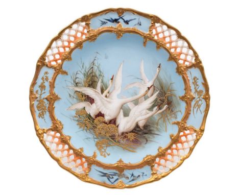 A Royal Worcester cabinet plate by Charley Baldwyn: painted with five swans in flight amongst reeds and grasses on a light bl