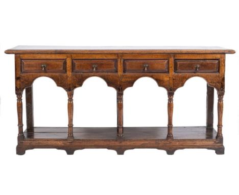An early 18th Century oak dresser base:, the top with a moulded edge, containing four short fielded panel drawers in the arca