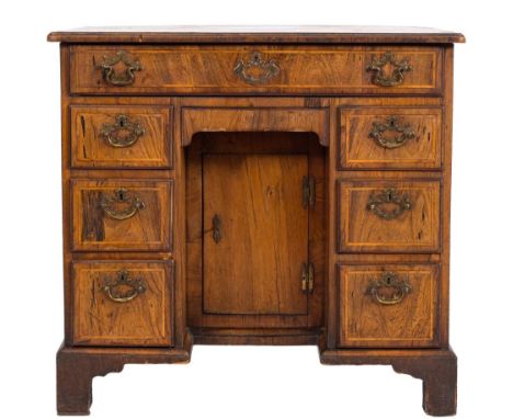 An early 18th Century walnut and diagonally banded kneehole desk:, of small size, the quarter veneered top with a crossbanded