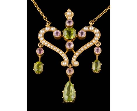 An Edwardian peridot, pink tourmaline and seed pearl open work pendant: of scroll design suspending peridot and pink tourmali