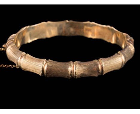 A 9ct gold bamboo-style bangle: with attached safety chain, approximately 16gms gross weight.  