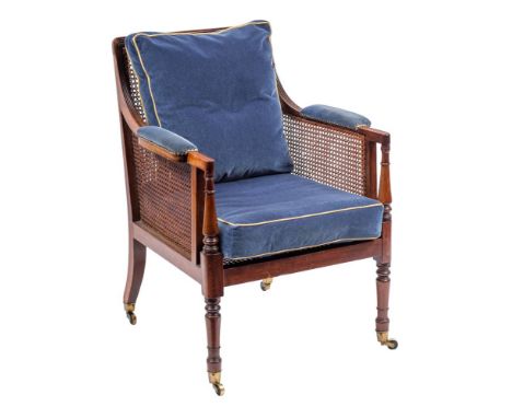 A Regency mahogany library Bergere armchair:, with a reeded frame, having a curved cane panel back, sides with padded arm sup