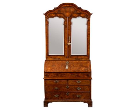 An early 18th Century burr and figured walnut and cross and feather banded bureau cabinet:, the upper part with a shaped arch