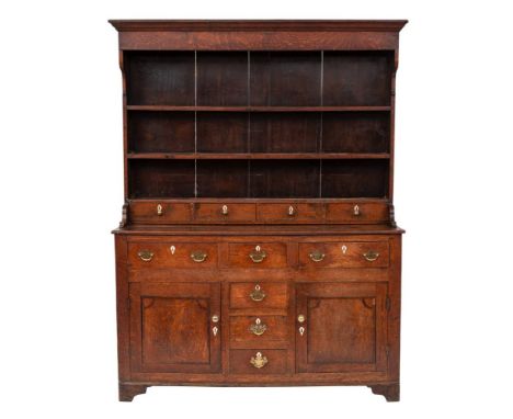 A late 18th Century oak dresser:, the shelved superstructure with a moulded cornice and fitted with four small drawers at bas