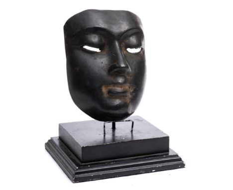 An Egyptian bronze mask: mounted on a stepped ebonised wood base, the mask 16.5cm. tall