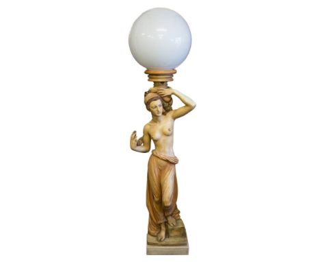 A resin figural  floor standing lamp of a semi-naked slave girl: holding a cornucopia shell on her shoulders, with opaque pla