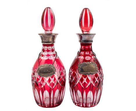 A pair of ruby and clear overlay glass decanters and stoppers: with plated mounts and labels, 29cm high.