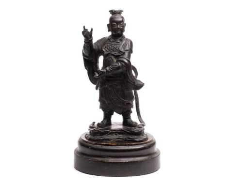 A Chinese bronze standing figure of a deity: wearing traditional costume on a naturalistic base, mounted on a wood plinth, ov