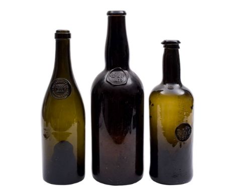 A group of three green glass sealed wine bottles: including a George III cylindrical bottle with seal 'R.H.C/1815', 27cm; a l