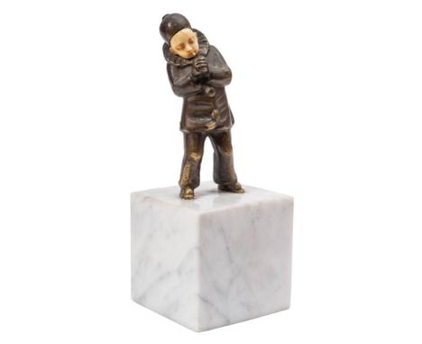 An Art Deco bronze and ivory figure of a young boy: dressed in a clown's suit, lighting a cigarette, raised on a square white