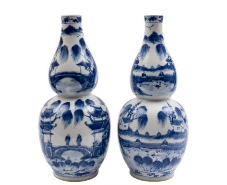 A pair of Chinese blue and white double gourd vases: each painted with figures in continuous lake landscapes with pagodas and