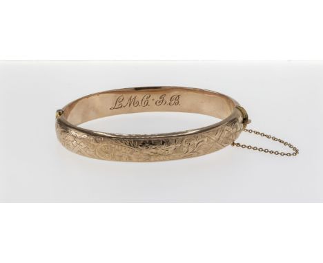 A hollow 9ct rose gold hinged bangle, with engraved floral and foliate detailing to the front panel and measuring approximate