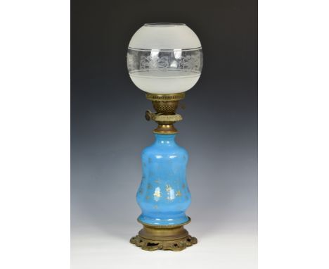 An antique blue glass oil lamp, with gilded foliate decoration, raised on cast metal circular base with bead and swag decorat