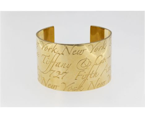 A Tiffany 18ct yellow gold Cuff Notes bangle, marked '© TIFFANY &amp; CO. 750', the wide, flat bangle engraved with four rows