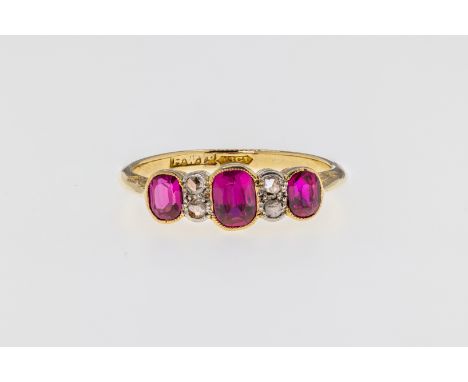 An 18ct gold, ruby and diamond 7 stone ring, featuring 3 graduated oval cut pink hued rubies with a pairs of rose cut diamond