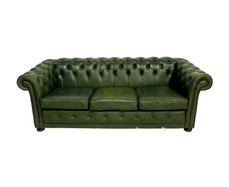 A green Chesterfield sofa by Wade, with brass studded scroll arms, wooden bun feet to front, castors to rear, 78 x 33¼in. (20