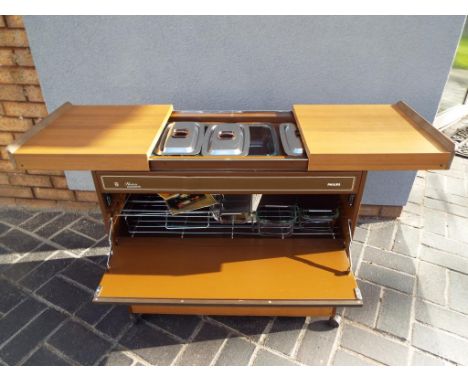 A Philips hostess trolley with sliding doors and drawer opening to reveal glass and stainless steel warming pots with manual,
