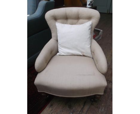 Low button backed armchair on castors, the padded arms, back and seat upholstered in beige contemporary cloth