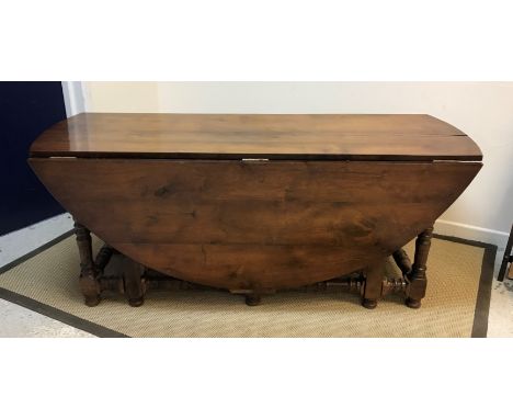 A 20th Century walnut oval double gate-leg dining table in the 18th Century manner, raised on turned and ringed supports unit