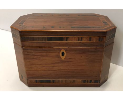 An early 19th Century rosewood and coromandel cross banded elongated octangoal tea caddy opening to reveal a two section lidd