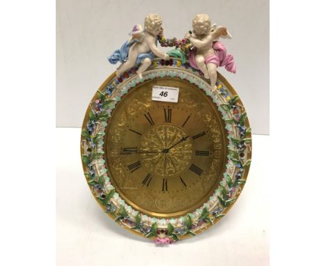 A Meissen porcelain framed oval easel backed clock decorated with floral sprays and cherubs, the brass dial set with Roman nu