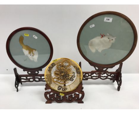 A gold coloured and enamel decorated filigree relief work plate with dragon decoration, 20 cm diameter, on a lacquered wooden