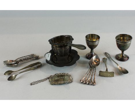 Various English and continental silver and metal items to include a tea strainer on stand, a sherry decanter label, tongs, pu