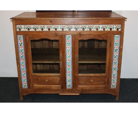 An Indian hardwood cabinet with tile decorated front and two glazed doors, 132cm wide by 107cm high