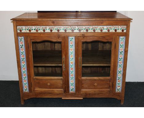 An Indian hardwood cabinet with tile decorated front and two glazed doors, 132cm wide by 107cm high