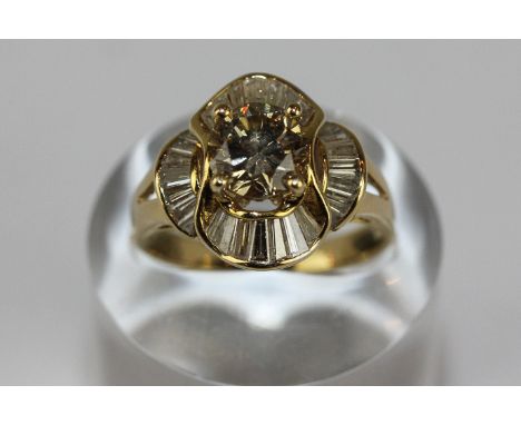 A diamond solitaire ring in raised claw mount and surround of baguette shaped diamonds on 750 gold band 