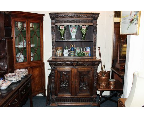 A Victorian carved oak bookcase with shelf enclosed by two coloured glass leaded light doors, the base with two drawers and c