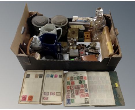 A box containing a decanter with silver collar, badges, hip flasks, stamp albums, whiskey jugs, vintage tins etc.