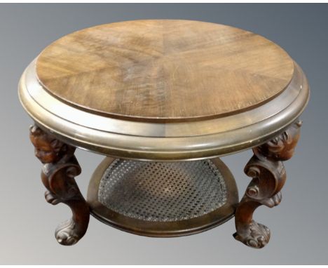 A continental oval beech two tier occasional table with bergere shelf on carved cherub legs.