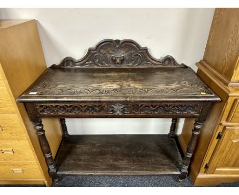 A 19th century heavily carved oak console table fitted with a drawer.